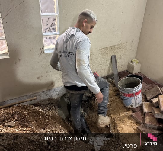 אדם עובד על תיקון צנרת עם דלי וכלים